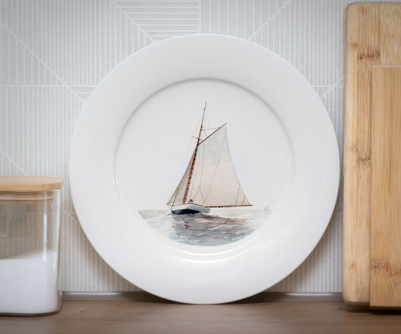White plate with a watercolor illustration of a sailboat at sea