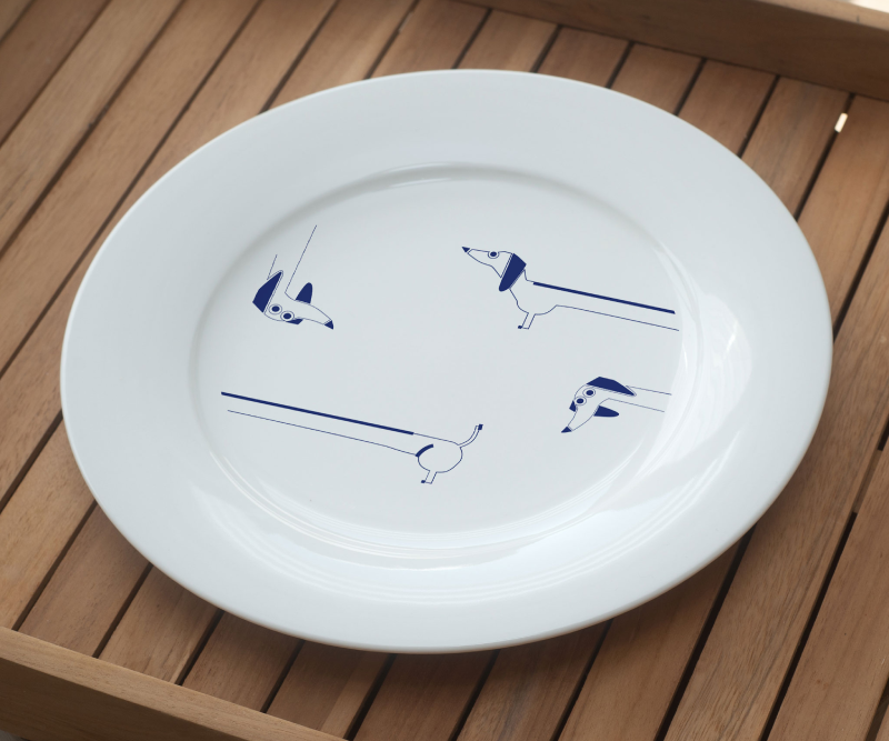White plate with a minimalist blue pattern featuring long dachshund-style dogs